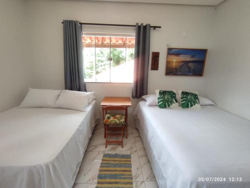 two beds in a room with a window at POUSADA NOSSO CANTO ALTER in Alter do Chao