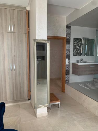 a bathroom with a mirror and a sink at Villa Jackbeach front mer in Dar Bouazza