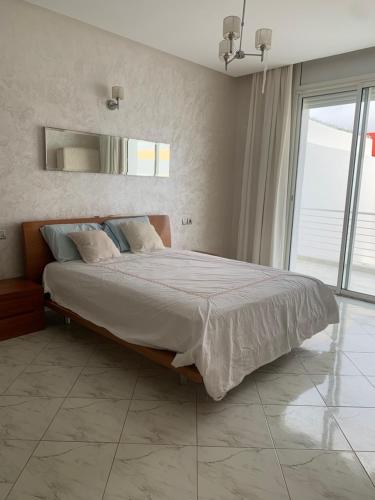 a bedroom with a large bed and a large window at Villa Jackbeach front mer in Dar Bouazza