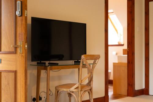 a television sitting on top of a table with a chair at Woodlands House with Hot Tub in Ballachulish