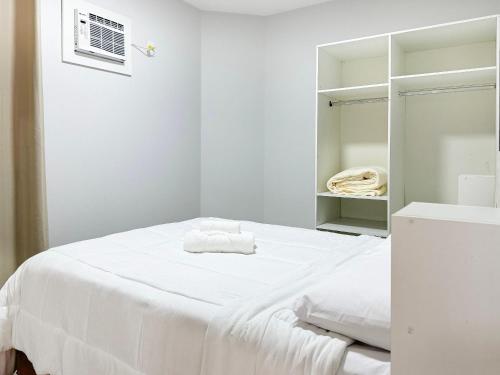 Cette chambre blanche comprend un lit et un miroir. dans l'établissement Res. Villa de Collina - Centro de Floripa - CEN002, à Florianópolis