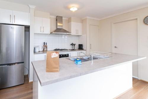a kitchen with white cabinets and a stainless steel refrigerator at Family Home for a Fiesta in Smithfield