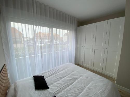 une chambre avec un lit et une grande fenêtre dans l'établissement Appartement proche plage, à Hardelot-Plage