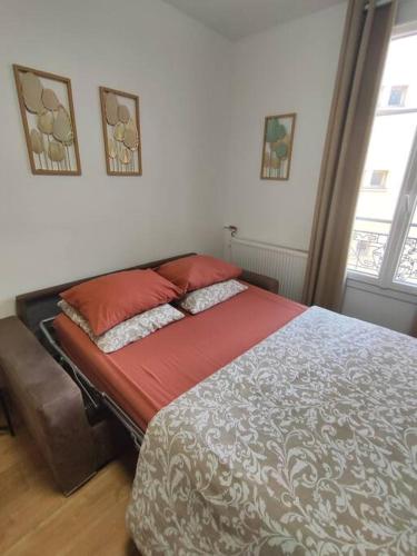 a bedroom with a bed with red sheets and pillows at Chez Caramel à Vincennes in Vincennes