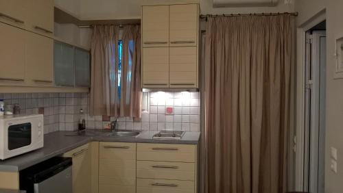 a small kitchen with a sink and a microwave at Antonia's Apartments in Yimnón
