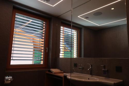 a bathroom with a sink and a mirror and two windows at Rumwaldhof - Wohnung Enzian in Solda