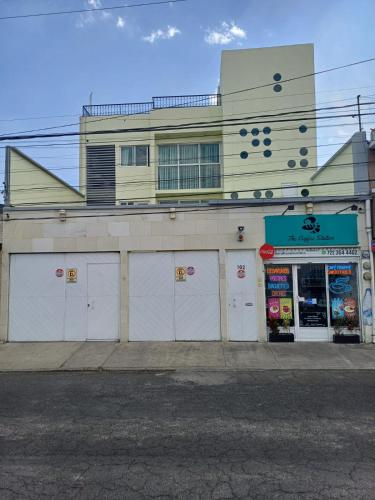 a building with white doors on a street at Departamento cómodo y completo en Toluca in Toluca