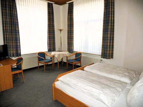 a hotel room with a bed and a table and chairs at Villa Daheim in Borkum