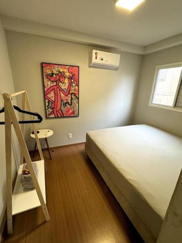 a bedroom with a bed and a ladder and a painting at CONDOMÍNIO SOLAR DI LUCCA lindo apartamento com AR CONDICIONADO e próximo a UEL in Londrina