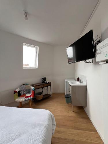 - une chambre avec un lit et une télévision murale dans l'établissement Kapsule - Olympe Suites & Spa Roubaix - Lille, à Roubaix