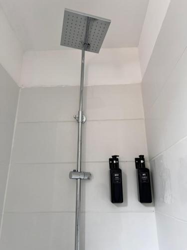 une douche avec deux bouteilles noires sur un mur dans l'établissement Kapsule - Olympe Suites & Spa Roubaix - Lille, à Roubaix