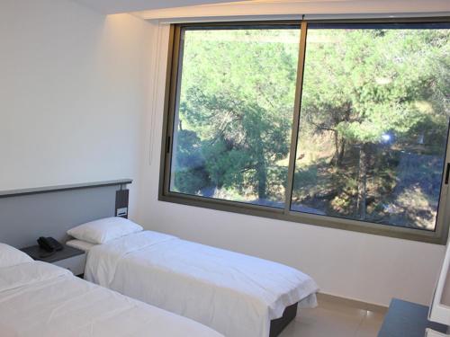 two beds in a room with a large window at Le Caravelle Beirut in Beirut