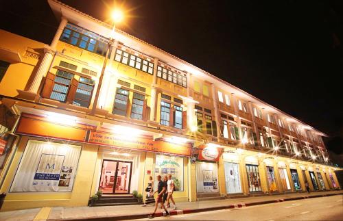 two people walking in front of a building at night at The Myth - Sud Sathorn in Bangkok