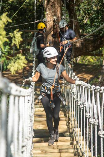 a woman crossing a rope bridge on a zip line at Bougainvillea 3103 Luxury Apartment - Reserva Conchal in Playa Conchal