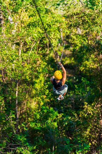 a person in a yellow helmet hanging from a rope at Bougainvillea 3103 Luxury Apartment - Reserva Conchal in Playa Conchal