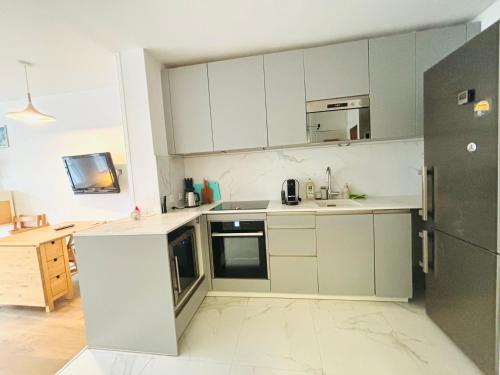  La cuisine est équipée de placards blancs et d'un réfrigérateur. dans l'établissement Dream Dwell Paris-Deluxe Studio 650m near Arc de Triomphe, à Paris