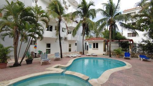 una piscina frente a un hotel con palmeras en Juan Dolio,Beach, Pool, 40"TV , Optic Internet, Relax, en Villas del Mar