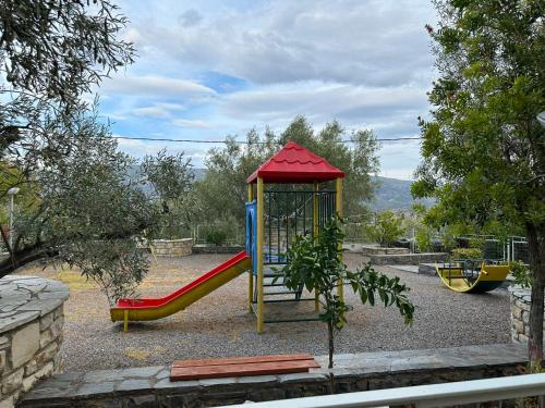 a playground with a slide and a swing at Antonia's Apartments in Yimnón
