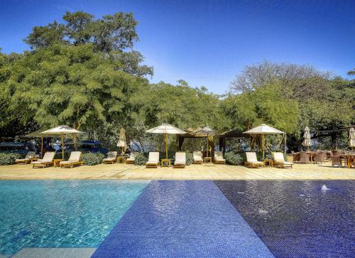 a swimming pool with lounge chairs and umbrellas next to at Aromo TH3 Townhouse with private pool Reserva Conchal in Playa Conchal