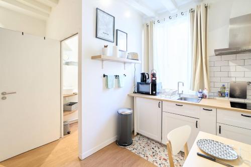 - une cuisine avec des placards blancs, un évier et une table dans l'établissement La Suite des Carmes - Studio cosy, à Nantes