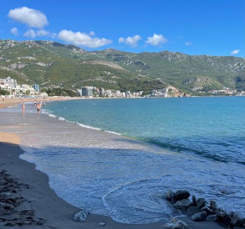 a beach with people walking on the sand and the water at Workation Panorama Escape in Budva