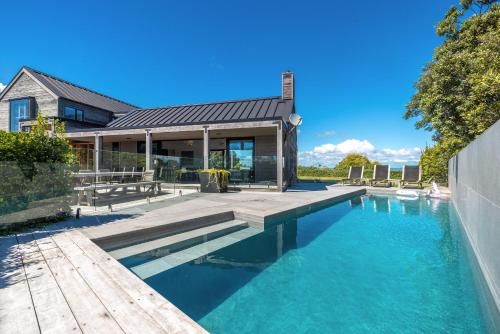 a home with a swimming pool and a house at Pacific Escape, Oneroa - Be My Guest Waiheke in Oneroa
