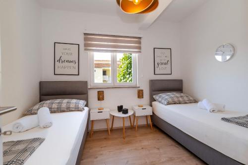 twee bedden in een kamer met witte muren bij Apartment Dora family only in Vodice