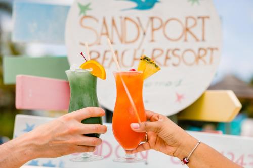 two people holding two cocktails in their hands at Sandyport Beach Resort in Nassau
