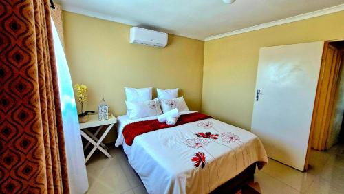 a bedroom with a bed with white and red sheets at Shisa Cottage in Durban