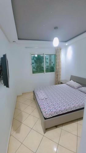 a bedroom with a bed and a tv in it at Appartement meublé harhora in El Harhoura