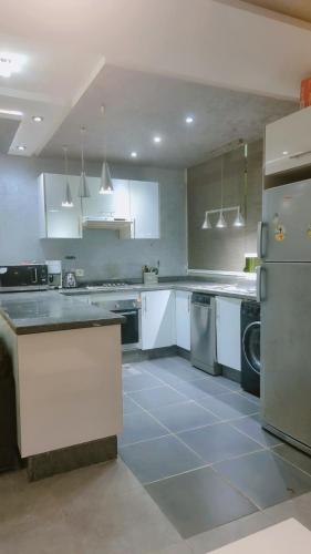 a large kitchen with white cabinets and appliances at Appartement meublé harhora in El Harhoura