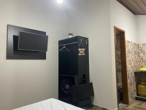 a room with a tv on a wall at Chalés Praias do Sana in Macaé