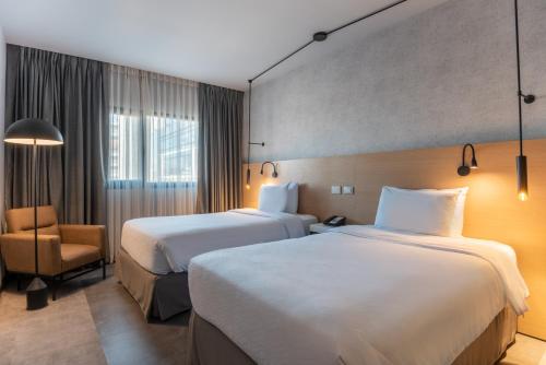 a hotel room with two beds and a chair at Novotel Bogota Parque 93 in Bogotá