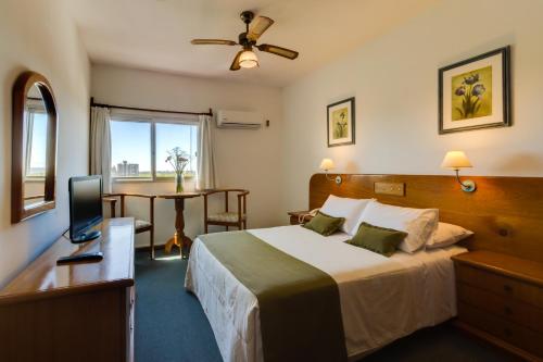 a hotel room with a bed and a desk with a television at Hotel Royal in Colonia del Sacramento