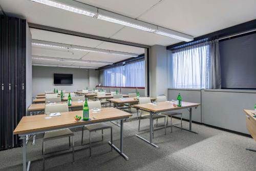 a classroom with tables and chairs with green bottles on them at NH Milano Congress Centre in Assago