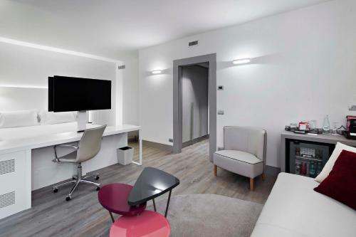 a living room with a desk with a computer and chairs at NH Milano Congress Centre in Assago