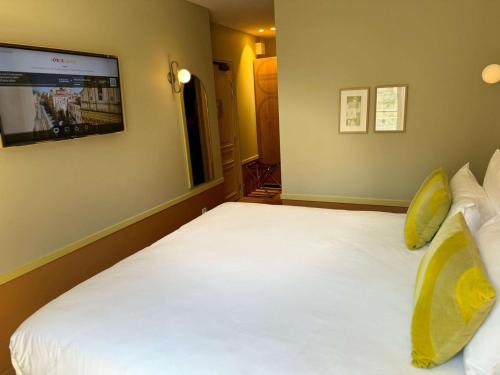 a bedroom with a white bed with a tv on the wall at Hotel De Cambis Best Western Premier Collection in Avignon