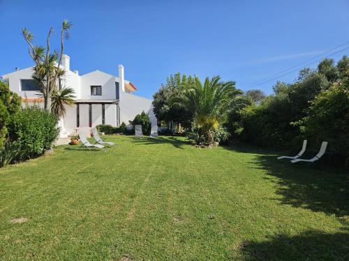a yard with chairs and a white house at Casa Seahorses b in Sintra