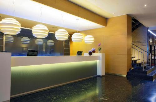 a lobby with a reception desk and pendant lights at NH Collection Villa de Bilbao in Bilbao