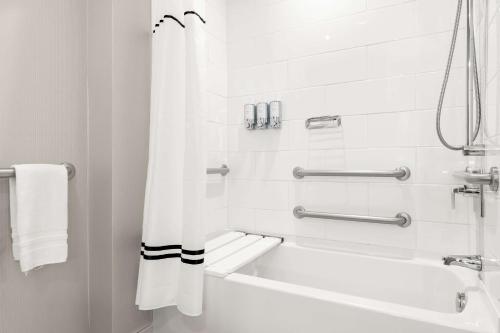 a white bathroom with a bath tub and a shower curtain at Sonesta Bee Cave Austin Hill Country in Bee Cave