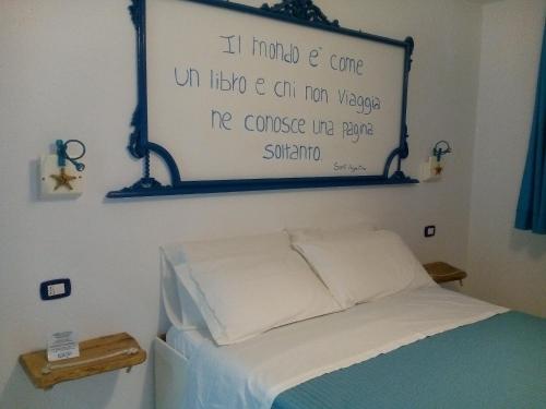 a bedroom with a bed with a sign on the wall at ControVento Rooms in Margherita di Savoia