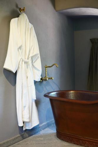 a robe hanging on a wall next to a bath tub at Hotel Piedras Neg in San Miguel de Allende