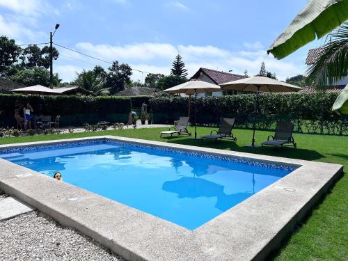 a swimming pool in a yard with chairs and umbrellas at Casa Otti-Olón in Olón
