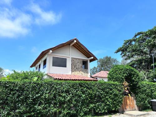 a house behind a hedge in front of a building at Casa Otti-Olón in Olón