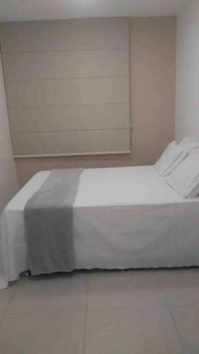 a bedroom with a white bed in a room at Vista espetacular em Itacimirim in Itacimirim