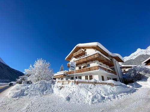a house covered in snow next to a road at Haus Arlberg in Pettneu am Arlberg
