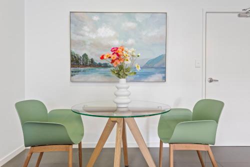 a dining room table with a vase of flowers on it at Cirque Boutique Apartments - Hosted by Coastal Letting Co. in Brisbane