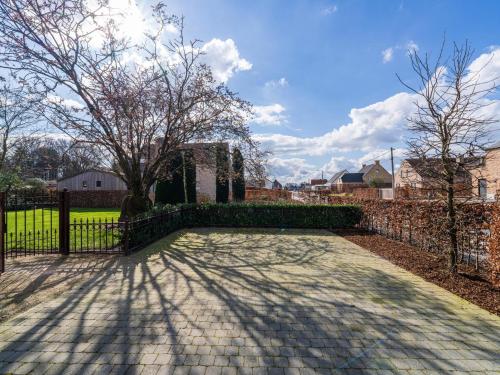 a fence with a tree and a brick sidewalk at Het Bruegelhof in Grote-Brogel