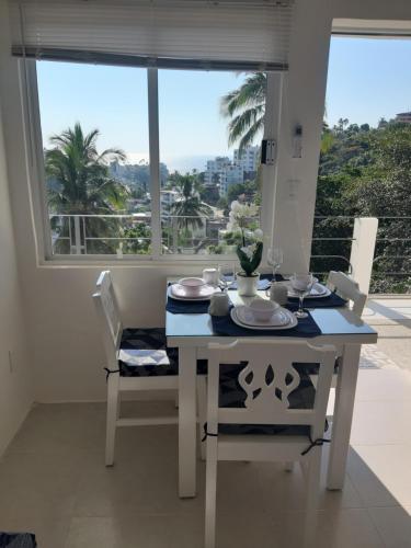 a white dining room table with a view of the ocean at Casablanca207 in Acapulco