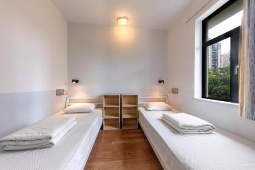 two beds in a room with a window at Shenzhen Loft Youth Hostel in Shenzhen